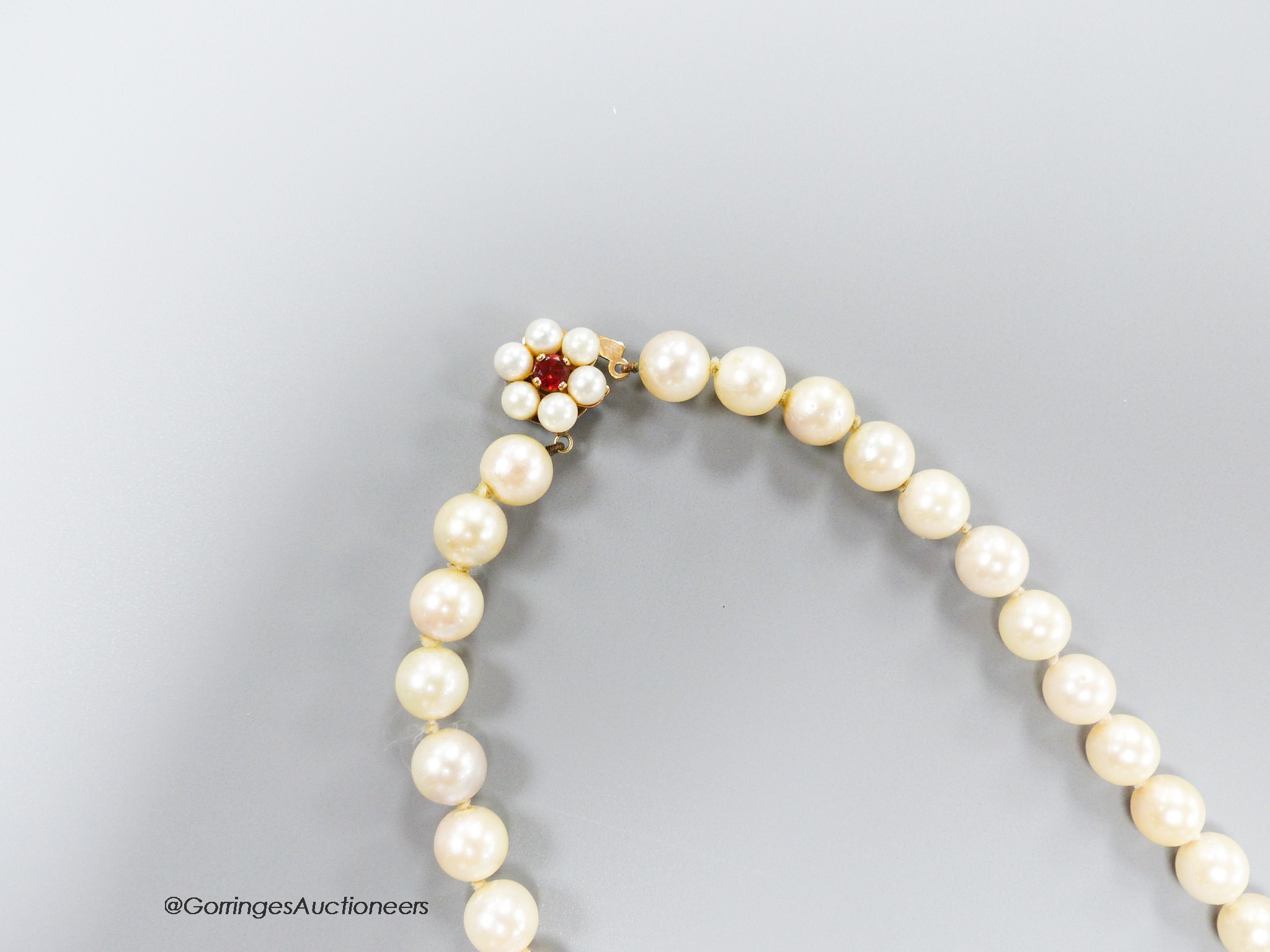 A single strand cultured pearl choker necklace, with garnet? and cultured pearl cluster set yellow metal clasp, 46cm, gross 40.9 grams.